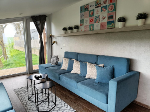 Salon moderne au Panorama Cottage de Gulperberg, Pays-Bas, avec canapé bleu et grandes portes vitrées.