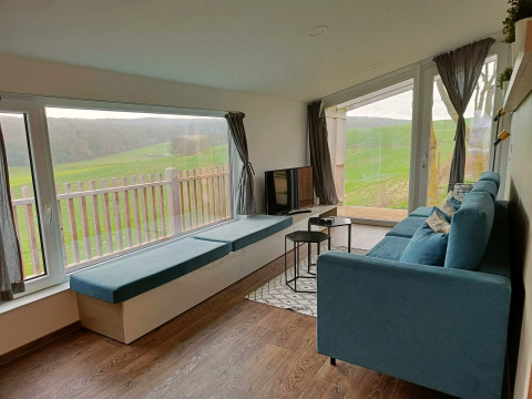 Modern living room at Panorama Cottage Gulperberg, Netherlands, with blue sofa and panoramic green views.