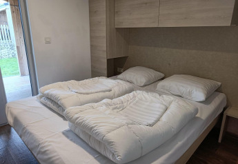 Letto matrimoniale con due piumoni al Panorama Cottage Gulperberg, Paesi Bassi, in una camera luminosa.