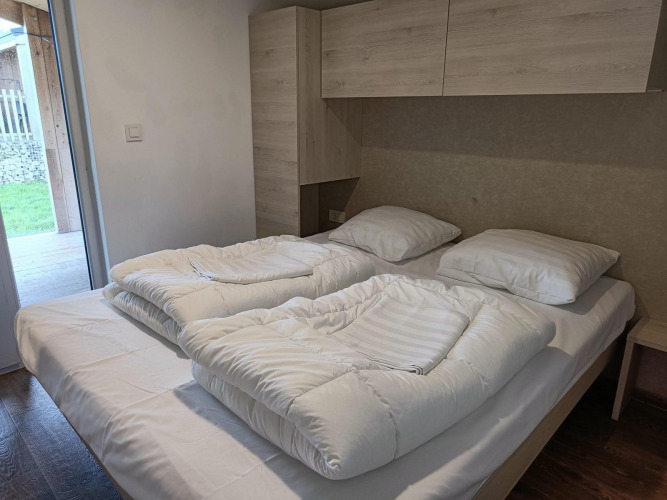 Cama doble en Panorama Cottage Gulperberg, Países Bajos, con dos edredones en una habitación luminosa.