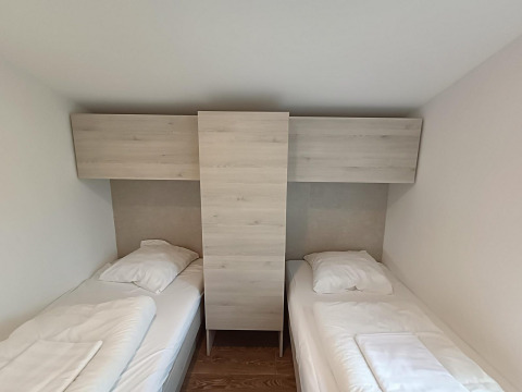 Dos camas individuales separadas por un armario de madera en Panorama Cottage, Gulperberg, Países Bajos.