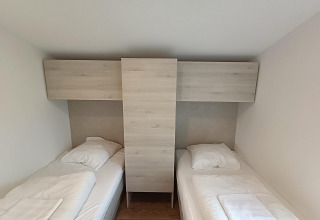 Dos camas individuales separadas por un armario de madera en Panorama Cottage, Gulperberg, Países Bajos.