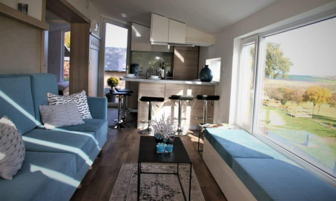 Indretning af Panorama Cottage på Gulperberg i Nederlandene med store vinduer og moderne møbler.