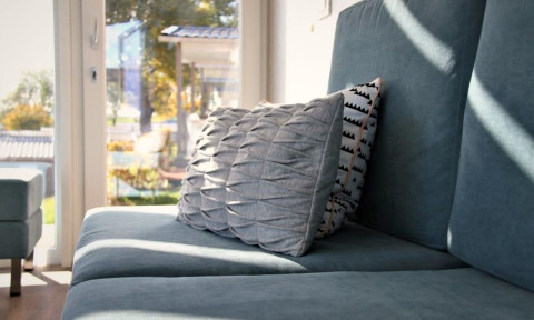 Cozy living area at Panorama Cottage, Gulperberg, Netherlands with a blue sofa and stylish pillows in sunlight.