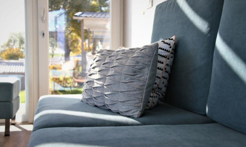 Hyggelig stue i Panorama Cottage ved Gulperberg, Holland, med blå sofa og elegante puder i sollys.