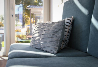 Zona relax al Panorama Cottage di Gulperberg, Paesi Bassi, con divano blu e cuscini eleganti alla luce.