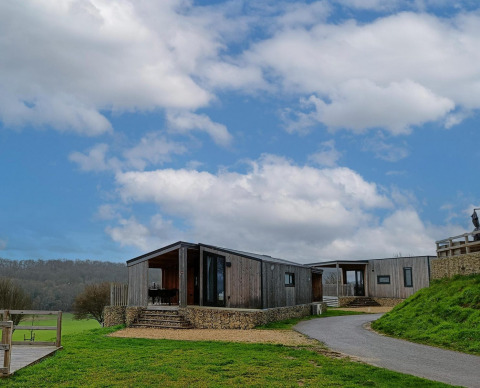 Panorama Cottage au Gulperberg, Pays-Bas, un lodge moderne en bois entouré de nature et ciel bleu.
