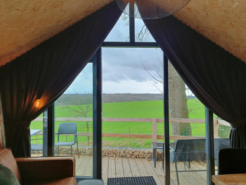 Vue depuis Solo Retreat à Gulperberg aux Pays-Bas, sur des champs verts à travers de grandes baies vitrées.