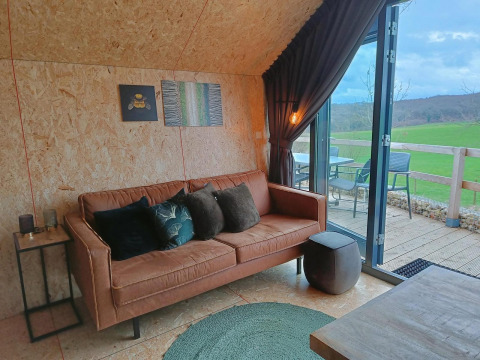Moderne lounge med sofa og udsigt til grøn mark, Solo Retreat ved Gulperberg, Holland, interiørfoto.