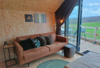 Moderne lounge med sofa og udsigt til grøn mark, Solo Retreat ved Gulperberg, Holland, interiørfoto.