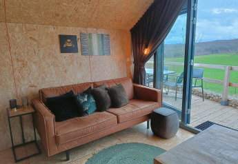 Moderne lounge med sofa og udsigt til grøn mark, Solo Retreat ved Gulperberg, Holland, interiørfoto.