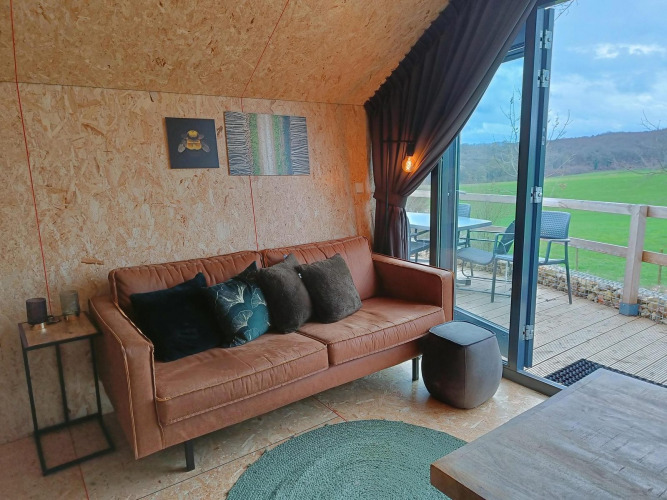 Salón moderno con sofá y vista al campo verde, Solo Retreat en Gulperberg, Países Bajos, foto interior.