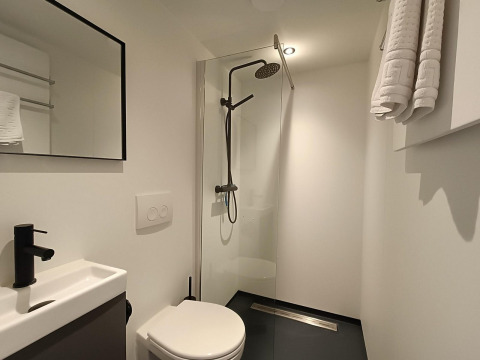 Baño moderno y minimalista en Solo Retreat en Gulperberg, Países Bajos, con ducha tipo lluvia.