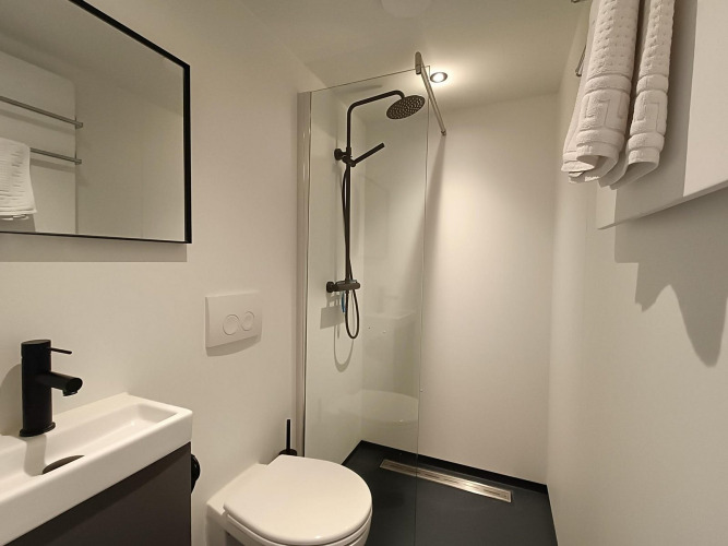 Baño moderno y minimalista en Solo Retreat en Gulperberg, Países Bajos, con ducha tipo lluvia.