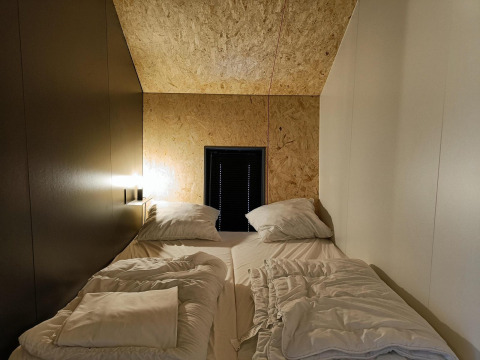 Habitación acogedora con dos camas individuales y paneles de madera en Solo Retreat, Gulperberg, Países Bajos.