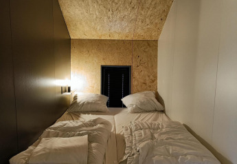 Soveområde med enkeltsenge og moderne træpaneler, Solo Retreat ved Gulperberg, Holland.