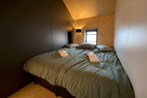 Minimalistisk soveværelse i Solo Retreat på Gulperberg, Holland, med seng, puder og blød belysning.