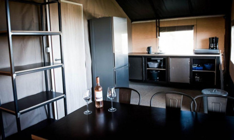 Modern kitchen and dining area in Panorama Lodge at Gulperberg, Netherlands, with wine and glasses on table.