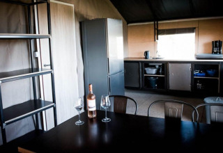 Cucina e zona pranzo moderna nella Panorama Lodge a Gulperberg, Paesi Bassi, con vino e bicchieri sul tavolo.