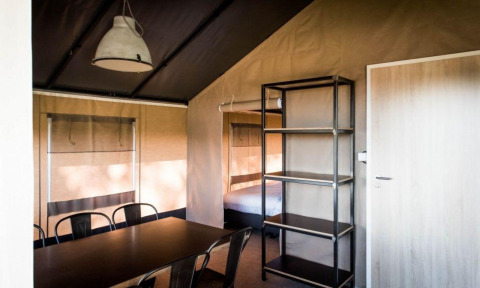 Interior de la Panorama Lodge en Gulperberg, Países Bajos, con mesa de comedor, sillas y cama.