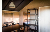 Interno della Panorama Lodge a Gulperberg, Paesi Bassi, con tavolo da pranzo, sedie e letto.