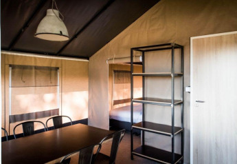 Interior de la Panorama Lodge en Gulperberg, Países Bajos, con mesa de comedor, sillas y cama.