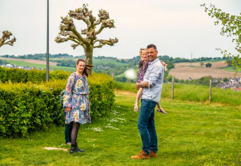 Famille profitant d’une escapade en glamping, entourée de verdure et de collines à l’arrière-plan.