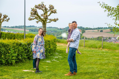 Famiglia che si gode una vacanza in glamping, circondata da prati verdi e colline sullo sfondo.
