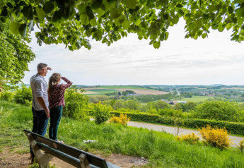 Ein Mann und ein Mädchen genießen den weiten Blick ins Grüne von einer Glamping-Unterkunft aus.