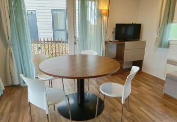 Eethoek met ronde tafel, vier witte stoelen en televisie in een lodge te Berghem, Gulperberg, Nederland.