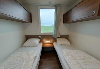 Chambre de lodge moderne à Gulperberg, Pays-Bas, deux lits simples, fenêtre avec vue et placards en bois.