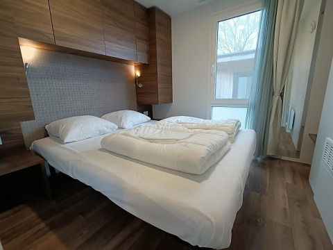 Camera moderna con arredamento in legno e letto matrimoniale nella lodge Berghem at Gulperberg, Paesi Bassi.
