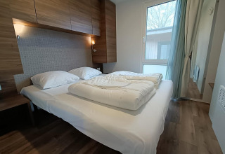 Camera moderna con arredamento in legno e letto matrimoniale nella lodge Berghem at Gulperberg, Paesi Bassi.