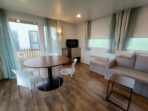 Moderne lodge-living met ronde eettafel, stoelen en TV in Berghem, Gulperberg, Nederland.