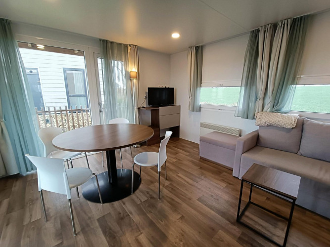 Sala de estar moderna en una cabaña con mesa de comedor, sofá y televisor en Berghem, Gulperberg, Países Bajos.