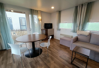 Sala de estar moderna en una cabaña con mesa de comedor, sofá y televisor en Berghem, Gulperberg, Países Bajos.