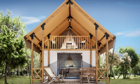 Charming Lodge de Montagne cabin with an inviting terrace, balcony, seating and lush green surroundings.