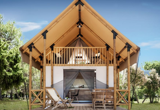Charming Lodge de Montagne cabin with an inviting terrace, balcony, seating and lush green surroundings.