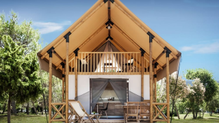 Acogedora cabaña Lodge de Montagne con terraza, sillas, balcón y rodeada de naturaleza exuberante.