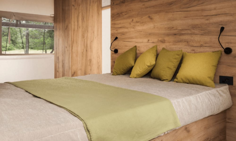 Cozy bedroom with wooden walls, green pillows and blanket at Lodge de Montagne, Gulperberg, Netherlands.