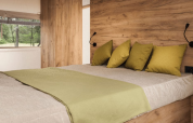 Chambre confortable avec murs en bois et coussins verts au Lodge de Montagne, Gulperberg, Pays-Bas.