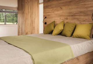 Cozy bedroom with wooden walls, green pillows and blanket at Lodge de Montagne, Gulperberg, Netherlands.