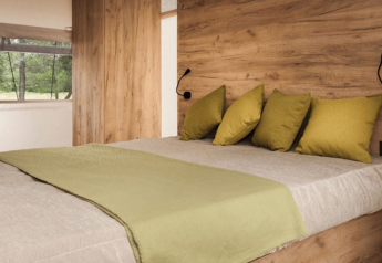 Dormitorio acogedor con paredes de madera y almohadas verdes en Lodge de Montagne, Gulperberg, Países Bajos.