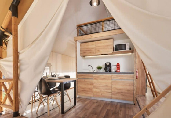 Indretningen af et Lodge de Montagne Petite safari-telt med moderne køkken og spiseplads.