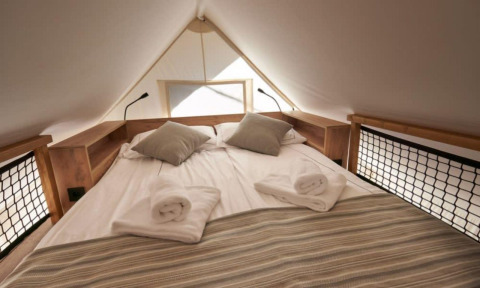 Gemütliches Bett mit frischer Bettwäsche im Lodge de Montagne Petite Safarizelt auf Gulperberg, Niederlande.
