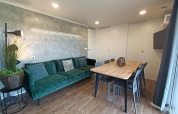 Woonkamer in Grandeur Chalet op Gulperberg, Nederland, met groene bank, eettafel en moderne inrichting.