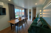 Moderne stue og spisestue i Grandeur Chalet ved Gulperberg, Nederlandene, med grøn sofa og store vinduer.