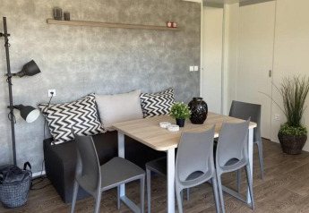 Gezellige eetruimte in Grandeur Chalet te Gulperberg, Nederland, met grijze stoelen, houten tafel en groen.