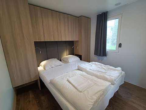 Modernes Schlafzimmer im Grandeur Chalet Gulperberg, Niederlande, mit Doppelbett und Holzschränken.