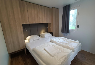 Modernes Schlafzimmer im Grandeur Chalet Gulperberg, Niederlande, mit Doppelbett und Holzschränken.
